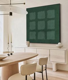 a dining room table with chairs and a large painting on the wall