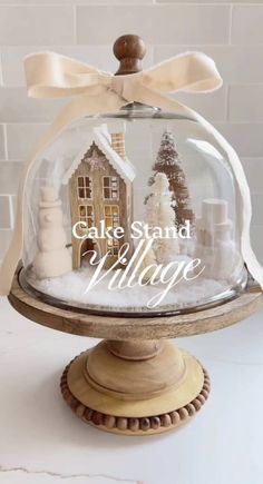 the cake stand village is under a glass dome with a bow on it's head