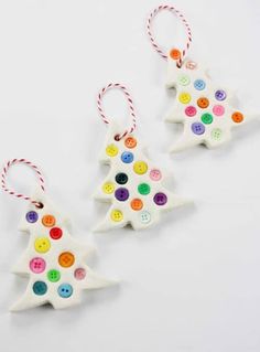 three christmas ornaments with buttons on them are sitting next to each other, one is white and the other is multicolored