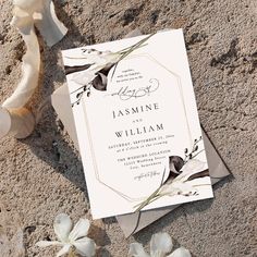 a wedding card on the sand with flowers