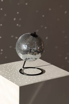 a silver disco ball sitting on top of a white block