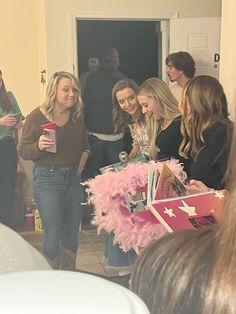 a group of women standing next to each other in front of a door with pink decorations