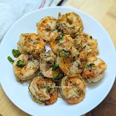 a white plate topped with shrimp and broccoli on top of a wooden table