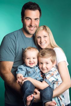 a man, woman and child posing for a family photo in front of a green background