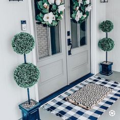 the front door is decorated with topiary balls and potted plants for an elegant touch