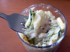 a fork in a cup filled with mashed potatoes and cucumber toppings