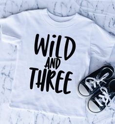 a t - shirt with the words wild and three written on it next to sneakers