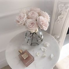 a white table topped with a vase filled with pink roses