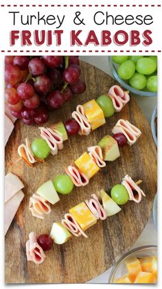 kid friendly cheese and meat kabobs with fruit on a cutting board next to grapes