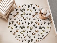 an animal print rug on the floor next to a crib with a teddy bear