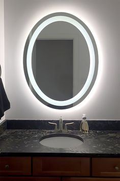 a bathroom sink with a lighted mirror above it