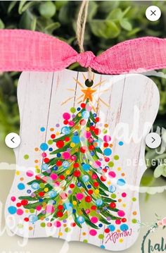 a wooden ornament with a christmas tree on it's side and pink ribbon