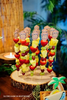 fruit skewers are arranged in the shape of people's hands on a tree stump