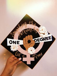 someone is holding up a graduation cap that says one degree at a time with flowers on it