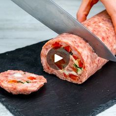 a person cutting up a piece of meat on top of a black slate board with a knife