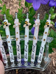 the bees are in their glass vases with writing on them and some purple flowers