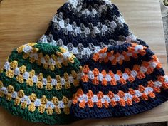 three crocheted hats sitting on top of a wooden table