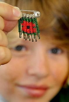 a young boy is holding up a piece of beaded brooch with a ladybug on it