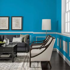 a living room with blue walls and white trim on the walls, furniture in front of a coffee table