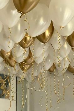 white and gold balloons are hanging from the ceiling