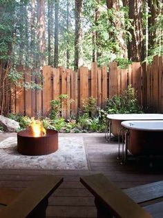 a fire pit sitting in the middle of a yard next to a fence and trees