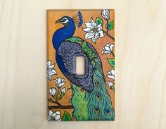 a decorative light switch cover with a peacock on it