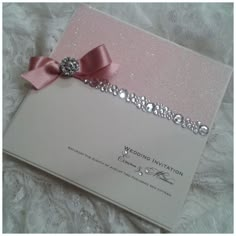 a wedding card with a pink ribbon and bow on the front is laying on a bed