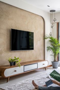 a person sitting on the floor in front of a tv with a plant next to it