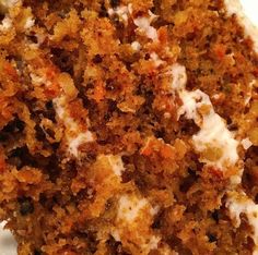 a piece of carrot cake sitting on top of a white plate covered in frosting