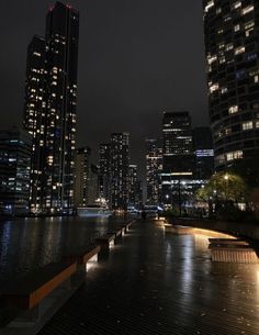 the city skyline is lit up at night with lights reflecting in the water and skyscrapers