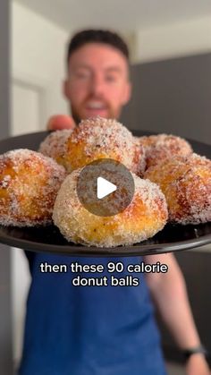 a man holding a plate full of donuts with sugar sprinkled on them