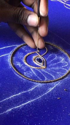 a person is working on a necklace with a small piece of gold wire attached to it