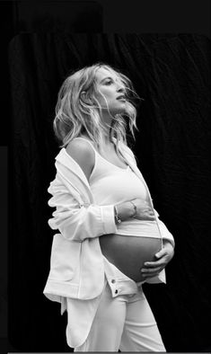 a pregnant woman in white clothes poses for a black and white photo with her belly exposed