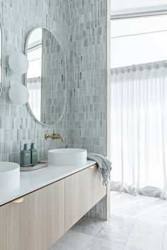 a bathroom with two sinks and a large mirror on the wall next to it's windows