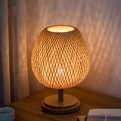 a wooden table with a lamp on it next to a book and coffee mugs