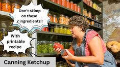 a woman holding a red tomato in front of a shelf filled with canned vegetables and jars