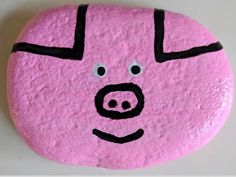 a pink rock with a pig's face painted on the side and black lines across it