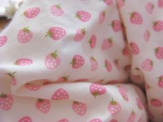 a pink strawberry print fabric with green leaves on it