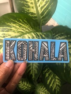 a sticker with the word kohlala in black and white on it next to a potted plant