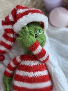 a green stuffed animal wearing a red and white striped hat