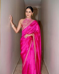 a woman in a pink sari is walking down the hallway with her hand on her hip