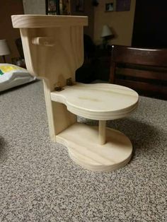 a wooden toilet sitting on top of a floor next to a night stand and bed