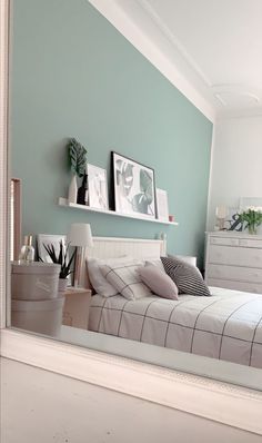 a bedroom with a large mirror reflecting the bed in it's room and plants on the wall