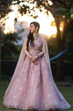 a woman in a pink gown standing on the grass