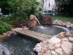 a small pond with a wooden bridge over it and water flowing from the top to the bottom