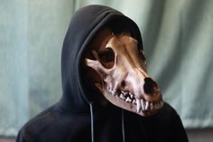 an animal skull wearing a black hoodie with its mouth open and teeth exposed to the side