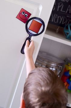 a young boy holding a magnifying glass in front of a magnet on a door