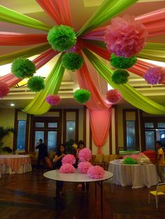 the ceiling is decorated with tissue flowers and pom poms in pink, green, and yellow colors