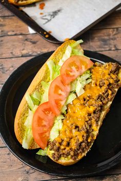 a black plate topped with a sandwich covered in cheese and lettuce