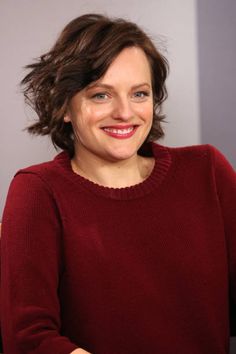 a woman sitting at a table with a plate of food in front of her and smiling